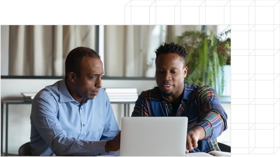 due uomini seduti ad un tavolo discutono davanti ad un laptop